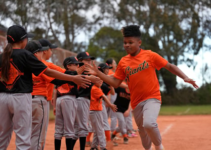 Boy high-fiving his team on a baseball field