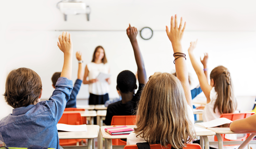 kids in classroom with raised hands