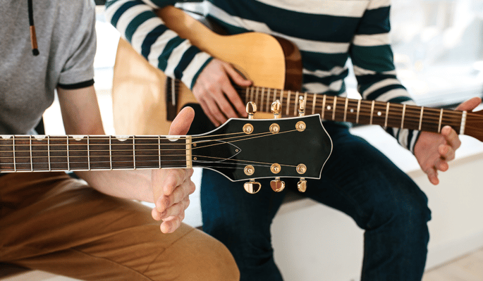 Two people practicing guitar