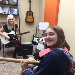 Student playing guitar with a teacher